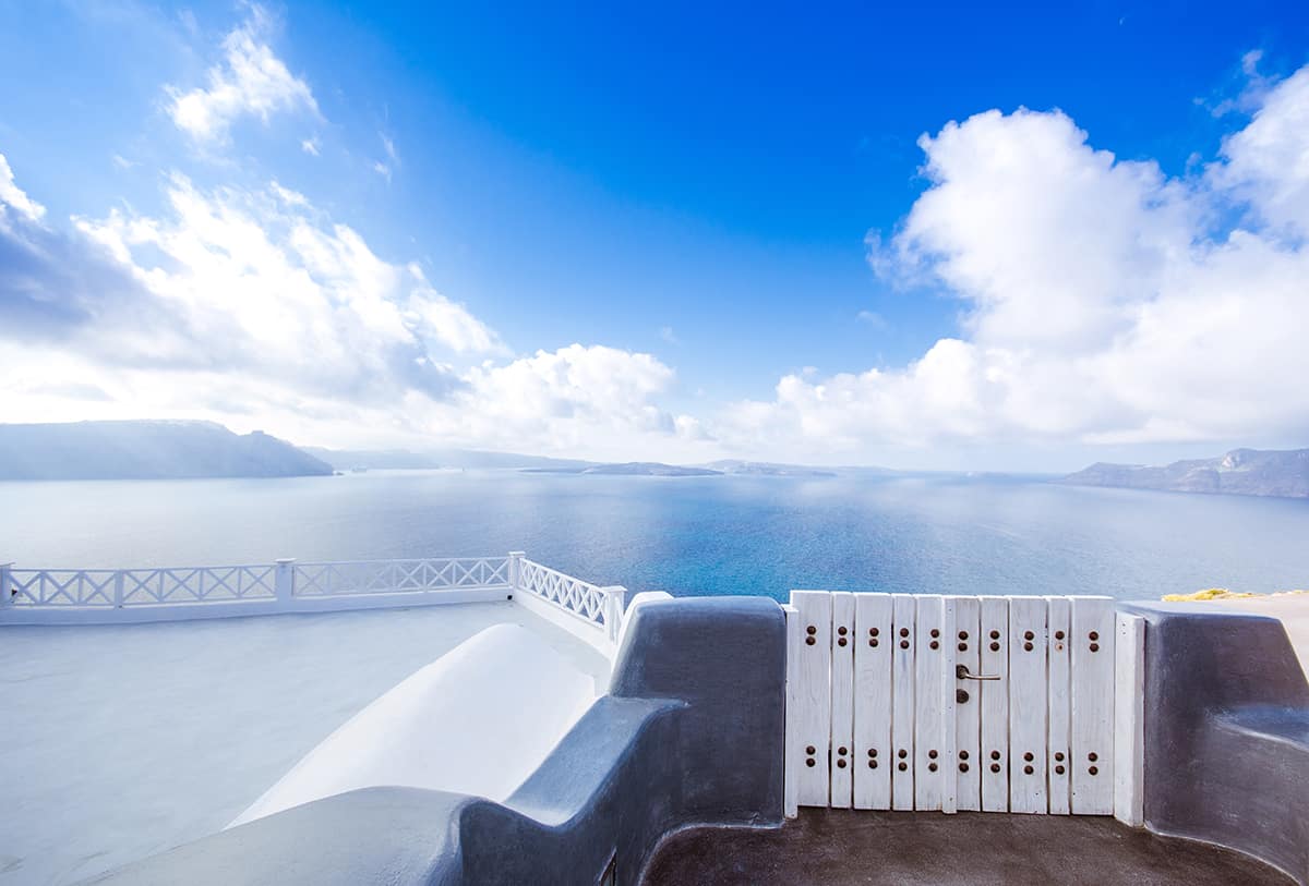 Beautiful Santorini blue sky looking from a shite topped building over the ocean.